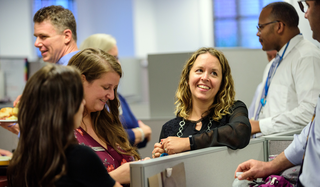 A group of coworkers smile and laugh while connecting at a VHB event.