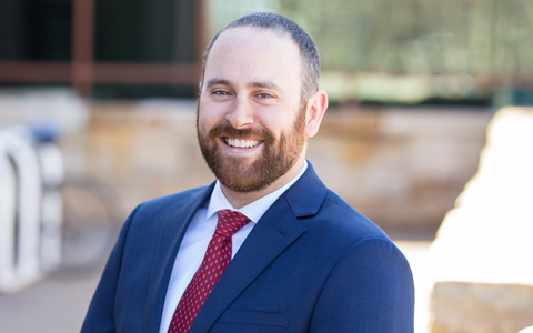 Aaron Guyette in a blue blazer, white shirt and red tie