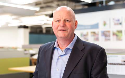 Tim Patch smiling in dark suit and striped shirt