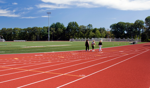 Three women walk along the synthetic track at Regis College.