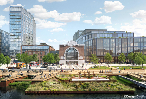 View from the waterfront depicting people walking on the boardwalks and using the public open space with the renovated turbine halls in the background set amongst the mixed-use development.