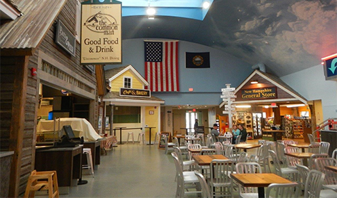 Tables and chairs sit in the middle of walk-up restaurants and a store at the welcome center.