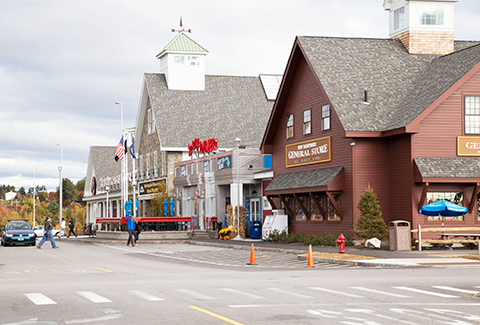 People walk past flagpoles at the building entrance of the Hooksett welcome center.