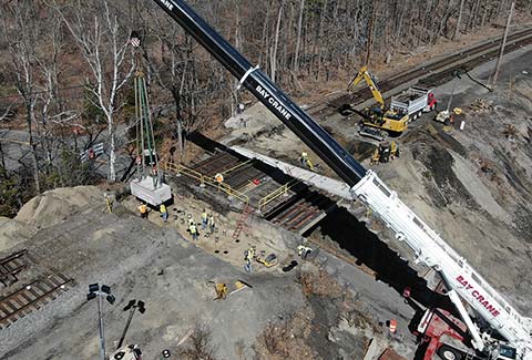 Aerial view of bridge rail replacement with construction workers and equipment.