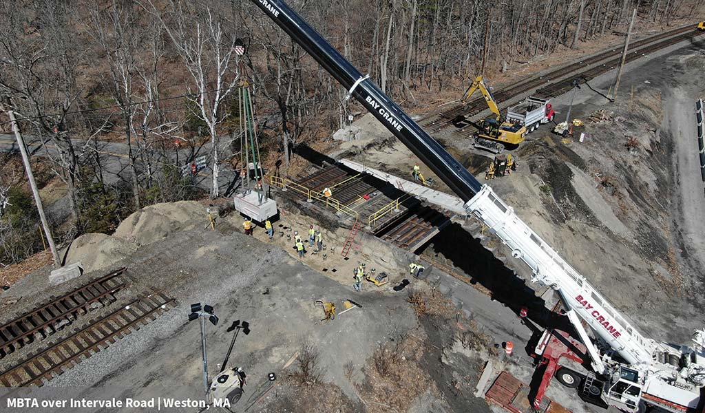 Aerial view of bridge rail replacement with construction workers and equipment.