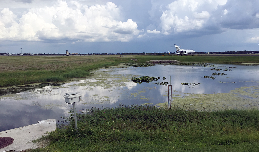 A plane sits on the runway past wetlands at Orlando Executive Airport.