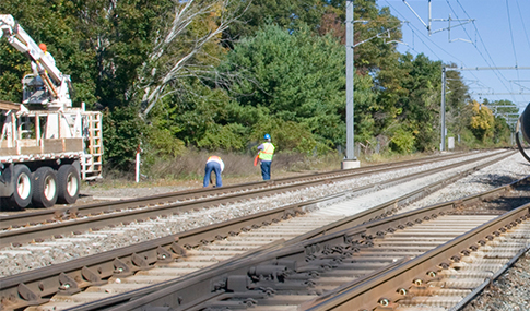 Two men work alongside railway tracks.