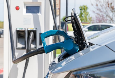 Electric car plugged in to charge battery at a charging station