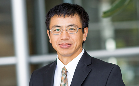 Baohong Wan standing outside wearing a black sports coat and tie.