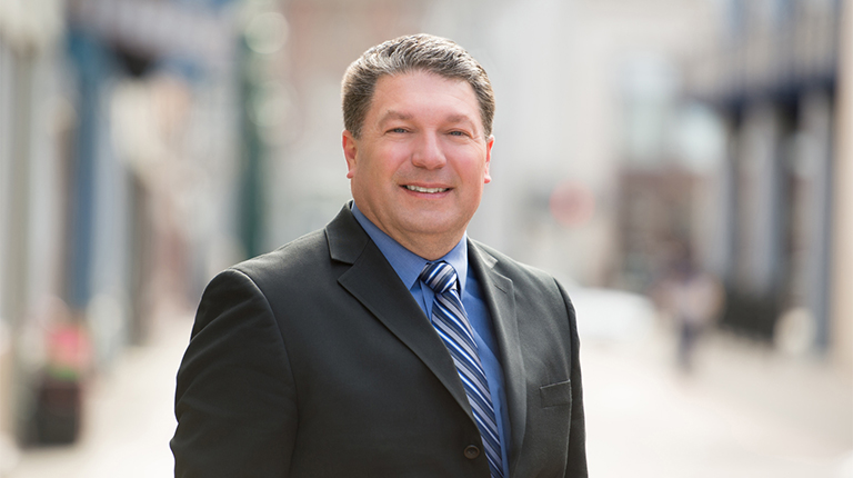 Larry Spraker in a dark blazer and blue shirt.