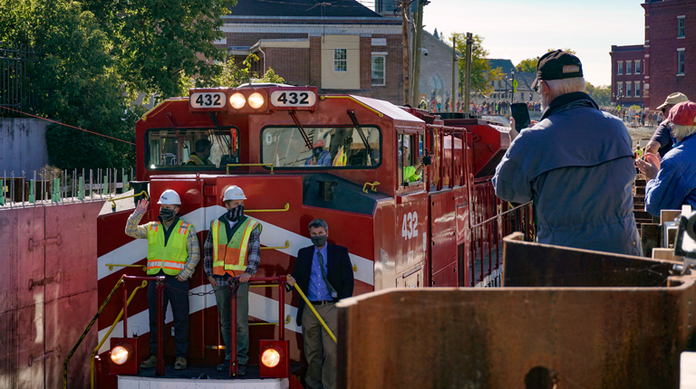 VHB and VTrans crew ride train through Middlebury, VT with excited town members watching following successful construction. 