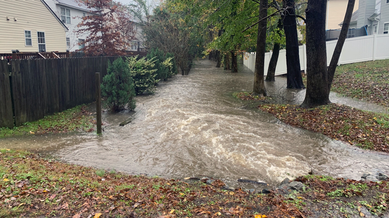 Flooding between fenced in backyards in residential neighborhood.