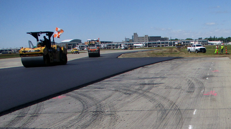 Construction progress at Runway 16-34 shows new pavement, with a view of Rhode Island T.F. Green Airport in the distance.