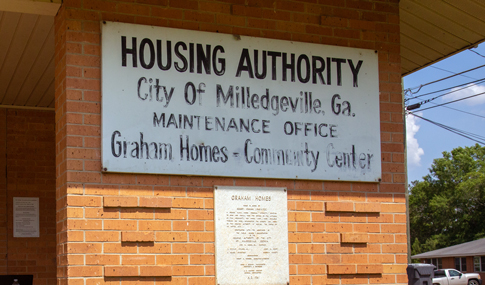 Original hand-painted sign and historical information plaque that are attached to the outside of the Graham Homes Community Center.