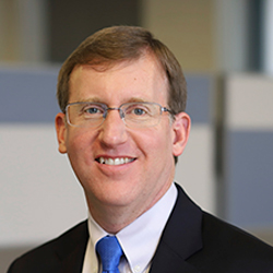 Darrell Smith in the office wearing a suit and blue tie. 