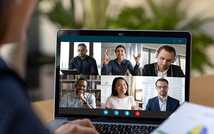 A laptop showing images of people participating in a virutal meeting. 