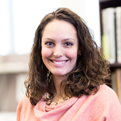 Brittany Gesner in the office wearing a peach top and floral jewelry.